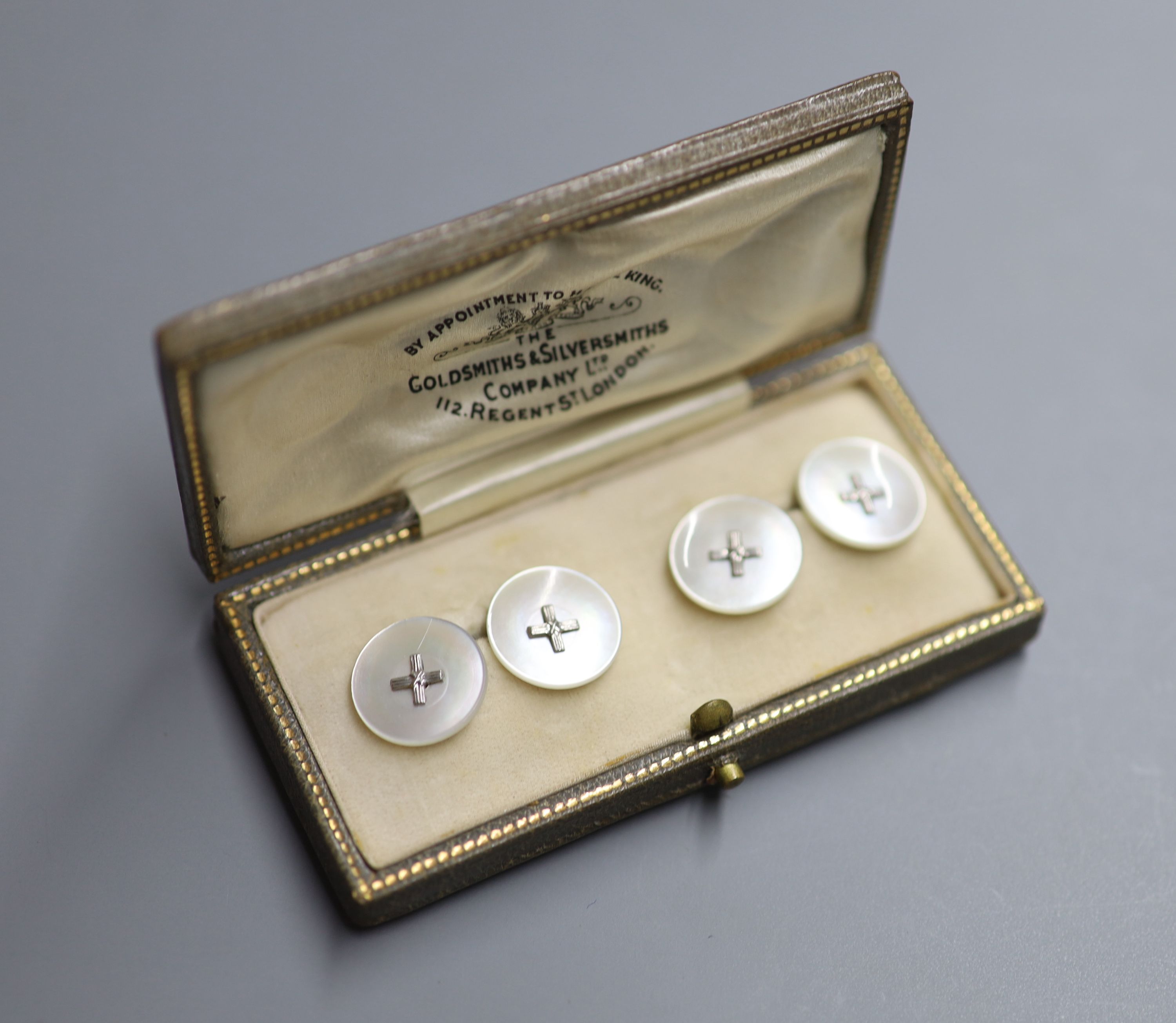 A pair of white metal mounted mother of pearl circular cufflinks, in Goldsmiths and Silversmiths fitted box.